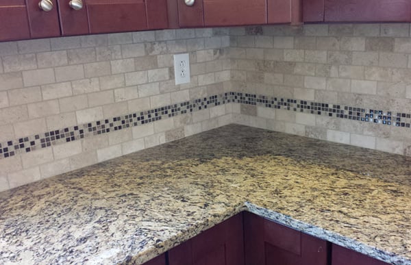 An all-over pattern in a Travertine subway tile with a decorative band to break up the installation and tie in the countertop pattern.