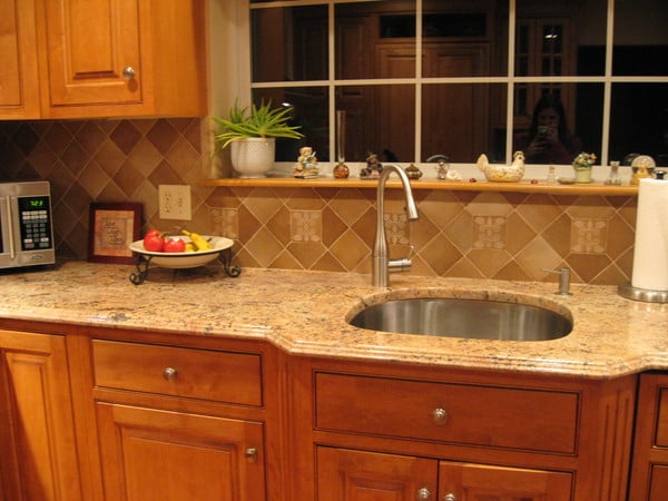 This kitchen backsplash features a related design element over the faucet area