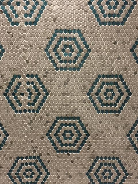 This image captures a small hexagon mosaic tile which creates a larger hexagon in a contrasting color. 