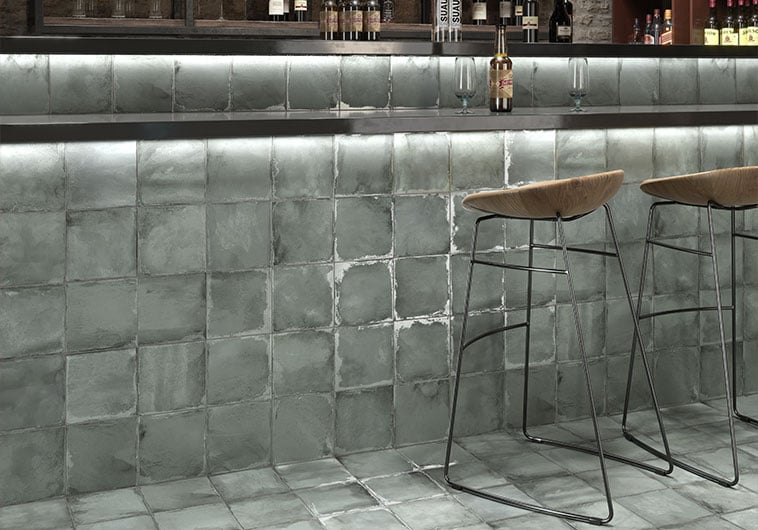 This lower backsplash installation under the bar in the image below not only captures a sage version of green but it also includes interesting weathered effects on the tile.