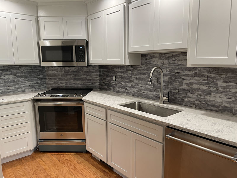 The glass tile in this backsplash dramatically ties together the white cabinets and the white Viatera Rococo polished countertop pattern.